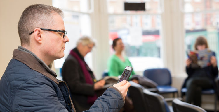 Man in waiting room looking at a mobile phone