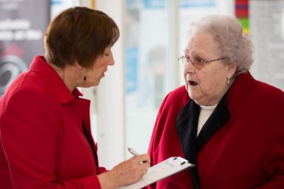A receptionist showing a lady how to fill in a form A receptionist showing a lady how to fill in a form